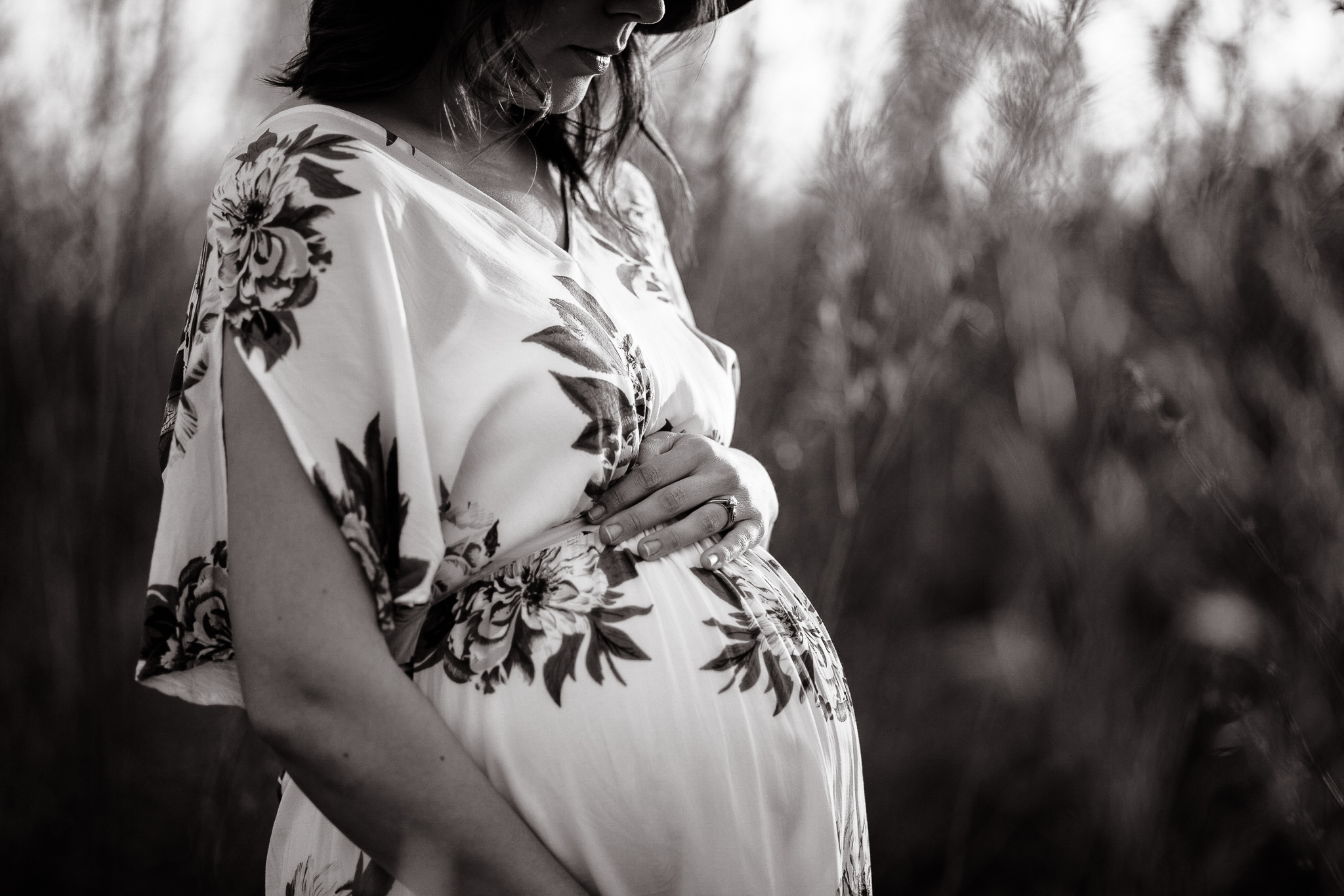 Expecting mother in the woods looking down at her belly.
